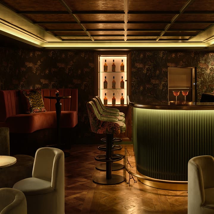 Elegantly lit cocktail bar interior with plush seating and decorative wallpaper