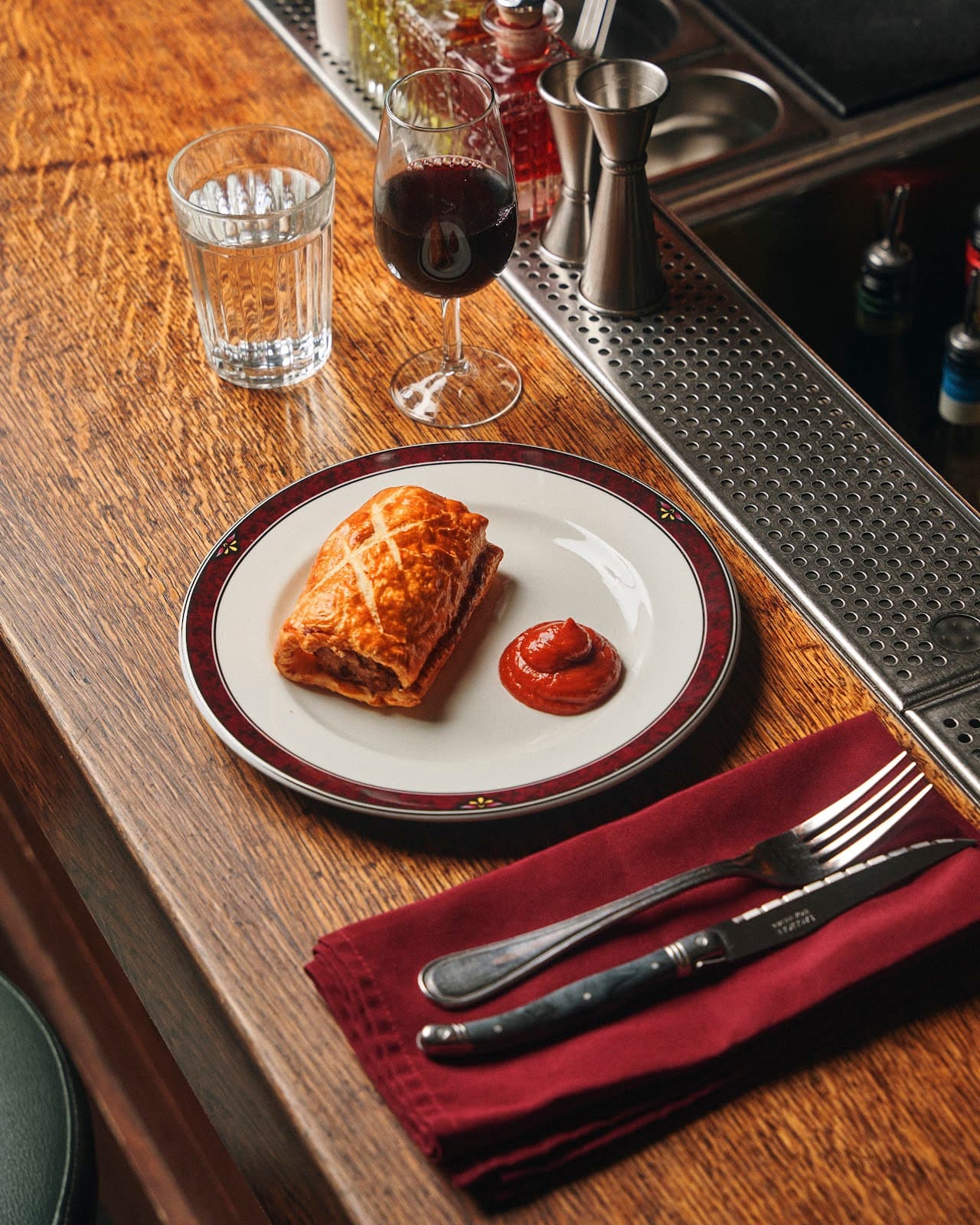 Bar counter with wine, water, and a pastry plated with ketchup. in Paris