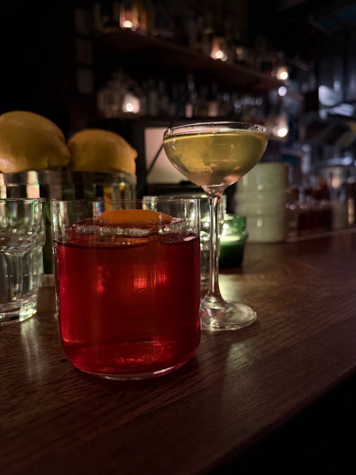 Close-up of two cocktails on a dimly lit bar counter in Paris
