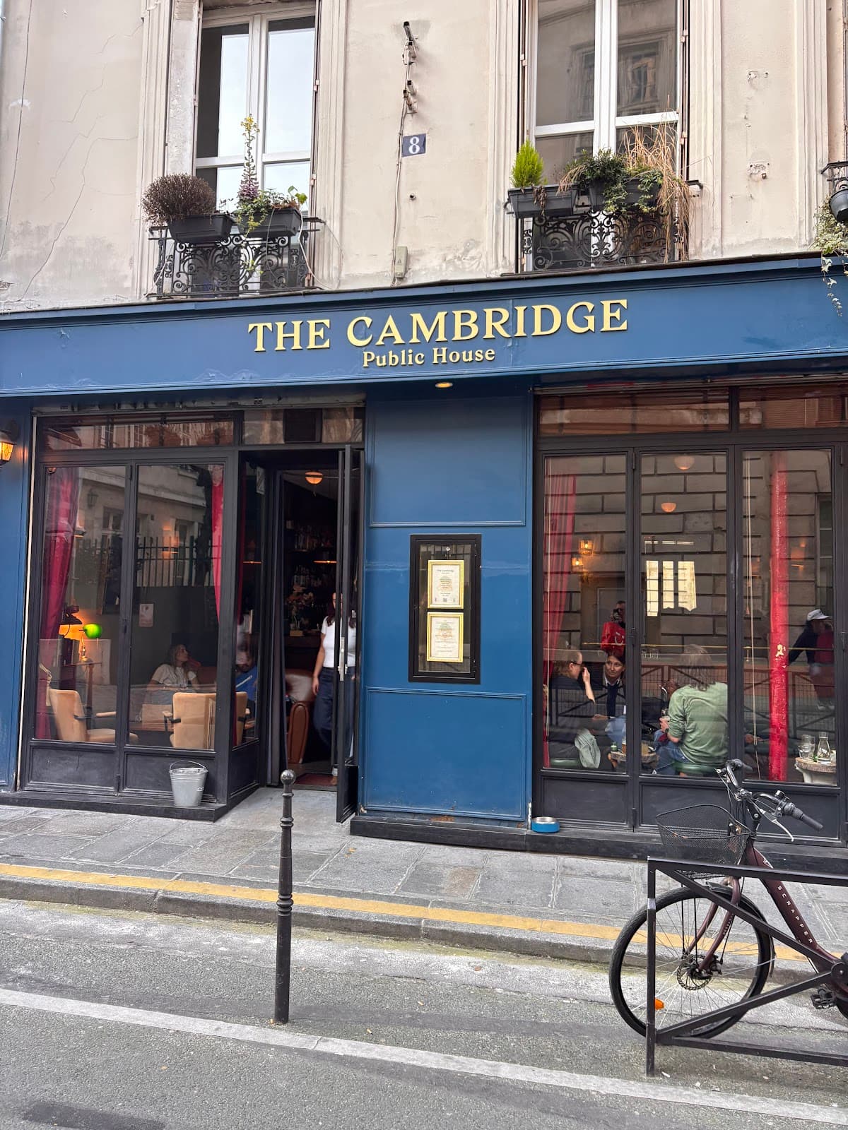 The Cambridge Public House exterior view on a street with bike and open doors in Paris