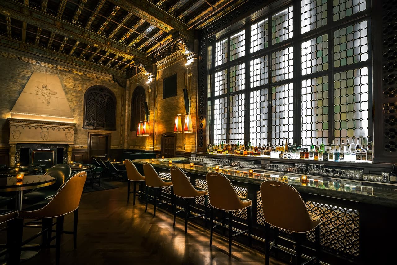 Elegant bar interior with high ceilings and a row of leather bar stools