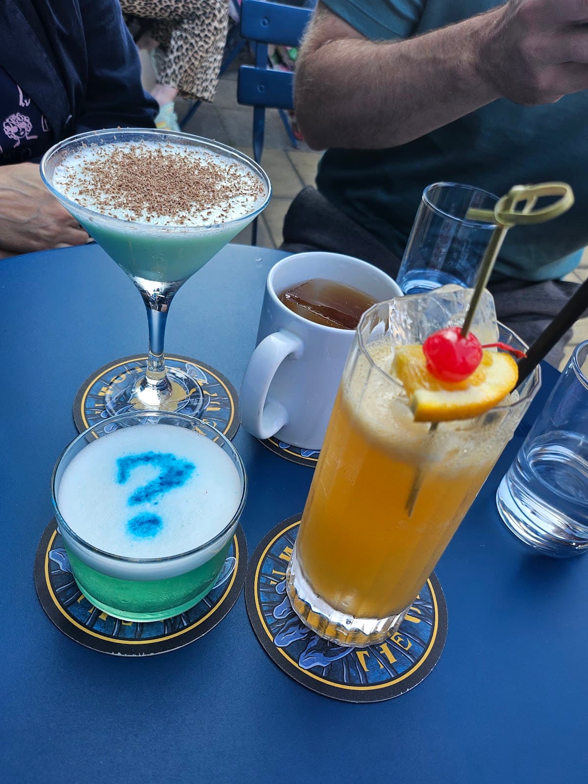 Various cocktails on a blue table with coasters in Edinburgh