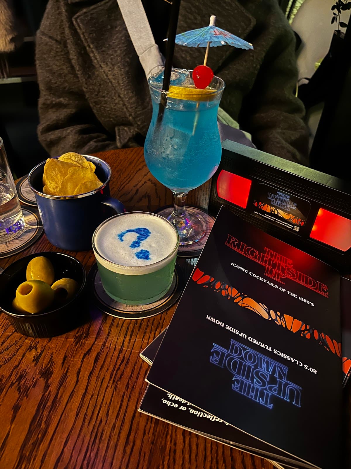 Colorful cocktails on a wooden table with a menu and snacks. in Edinburgh
