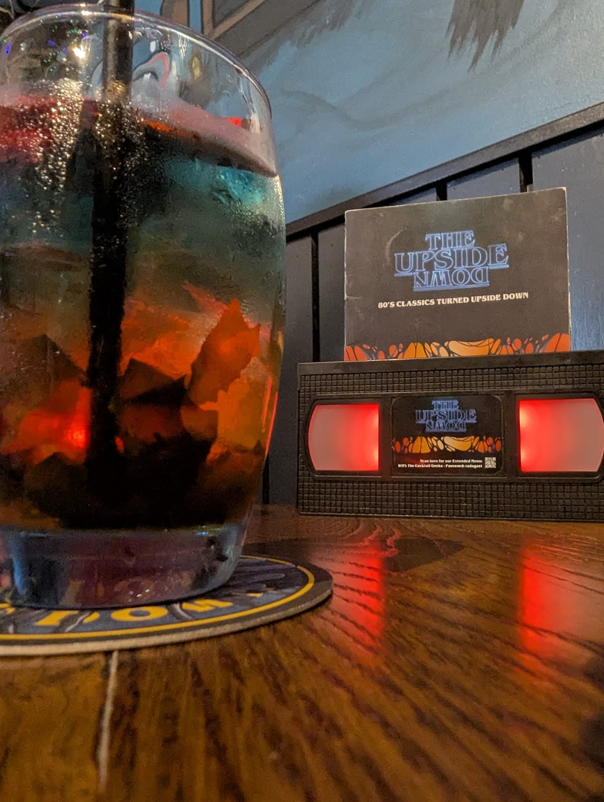 Colorful cocktail on a wooden table with Upside Down logo in the background in Edinburgh