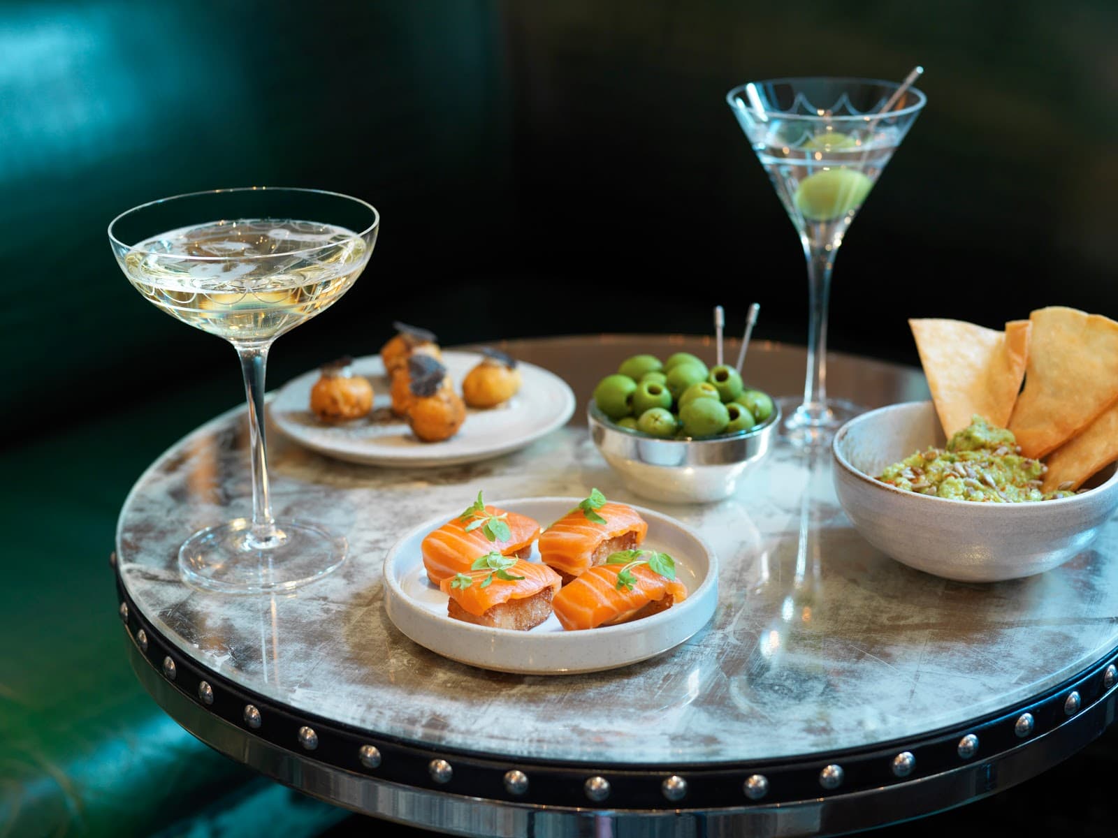 Cocktail and appetizers on a round metallic table at a premium bar in London