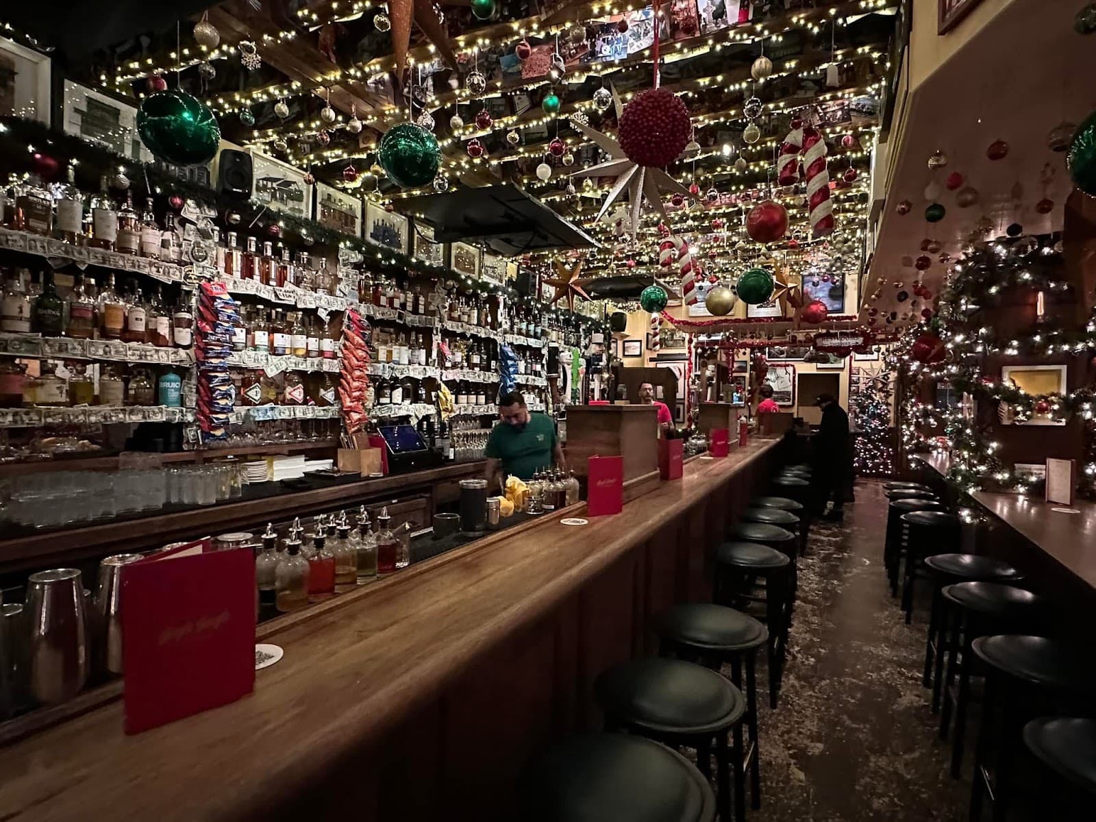 Festively decorated bar interior with shelves full of bottles and a long counter in New York