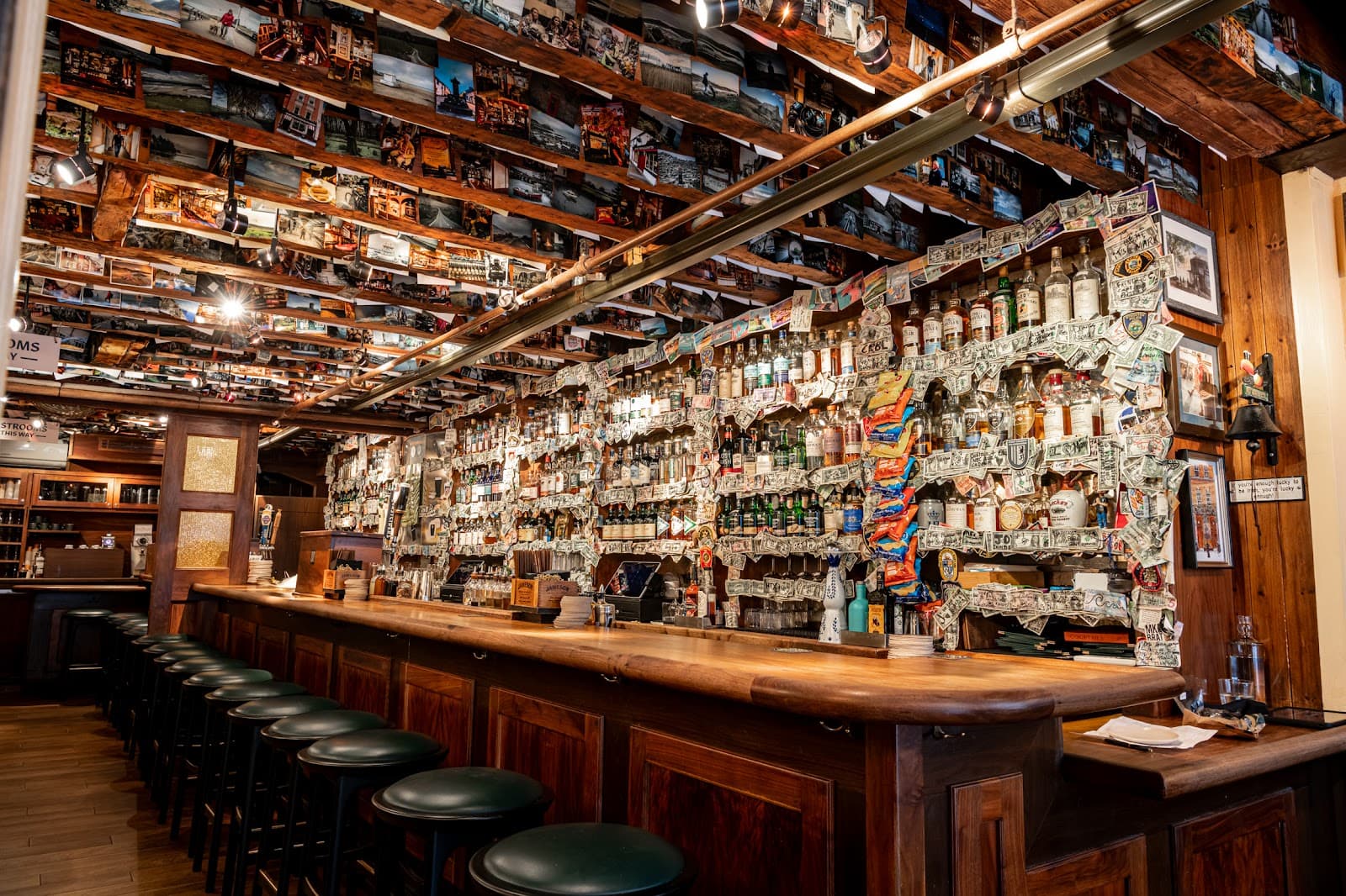 Lively bar with bottles, decorated walls, and ceiling photos