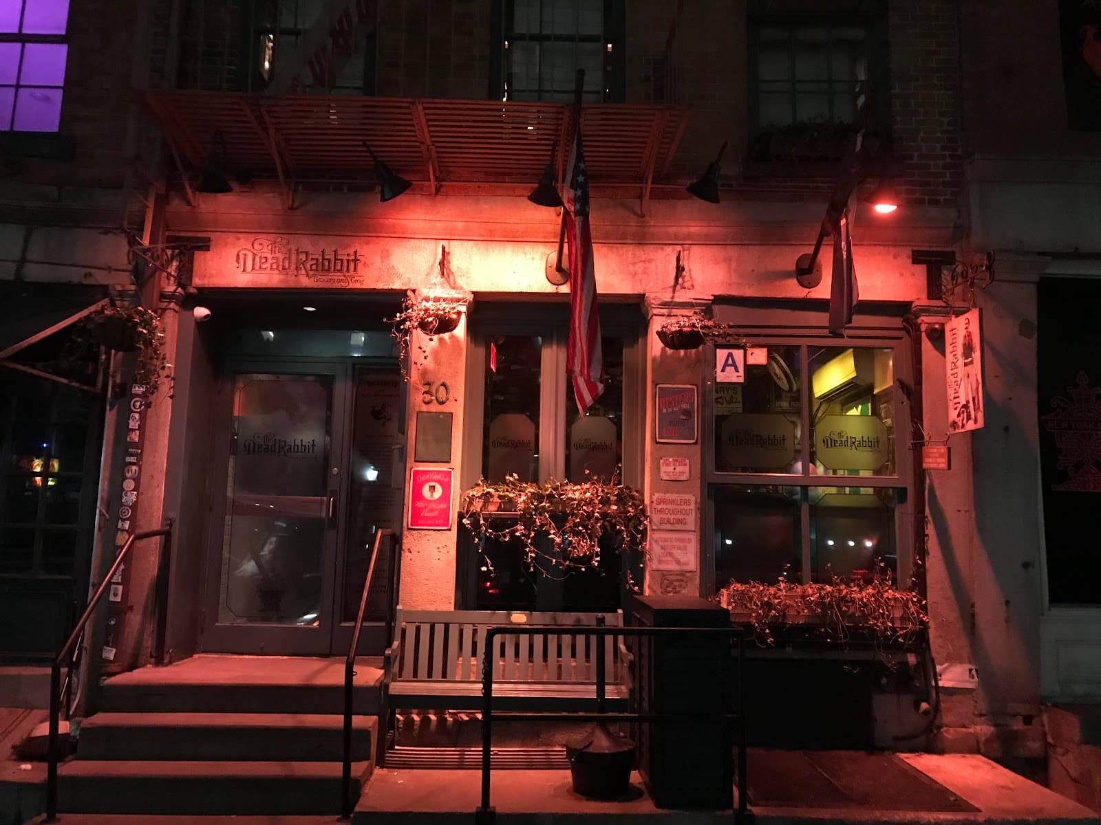 Exterior of The Dead Rabbit cocktail bar at night with warm lighting in New York
