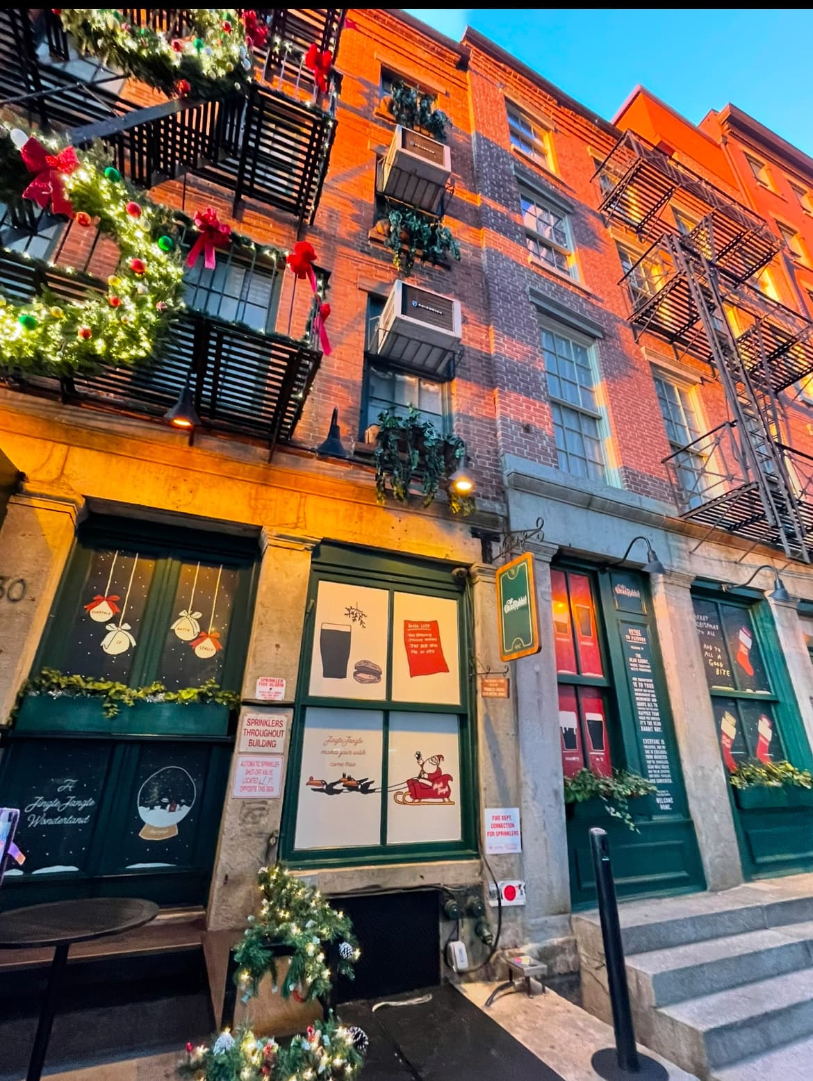 Festively decorated brick building exterior with fire escapes and holiday wreaths. in New York