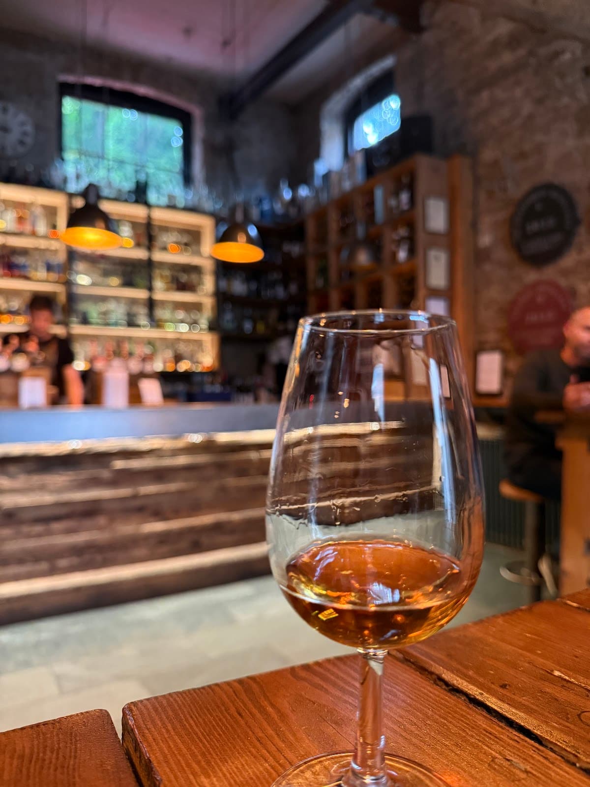 Glass of whiskey on wooden table with bar in background in Edinburgh