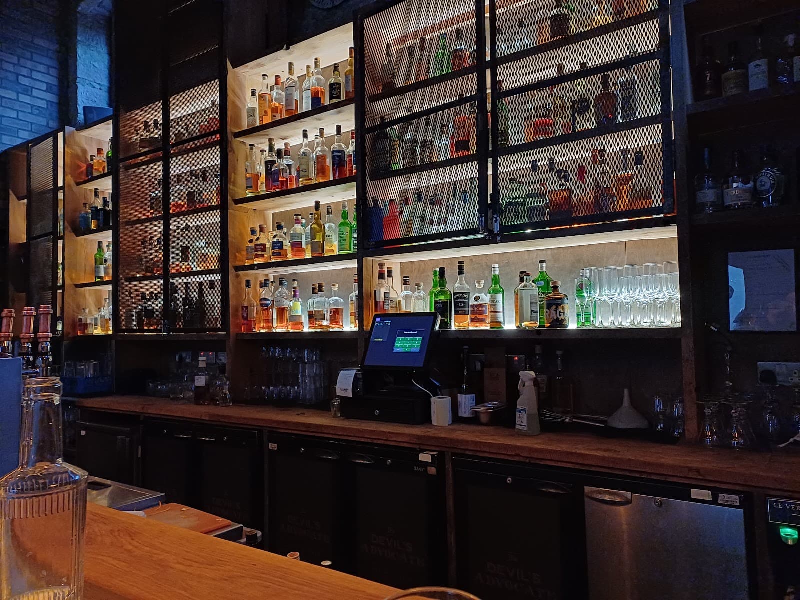 Bar counter with illuminated shelves of liquor bottles and glassware in Edinburgh