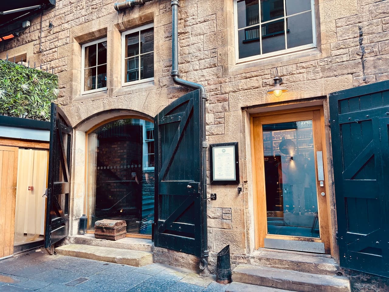 Charming stone facade with wooden doors and windows of a cocktail bar exterior in Edinburgh