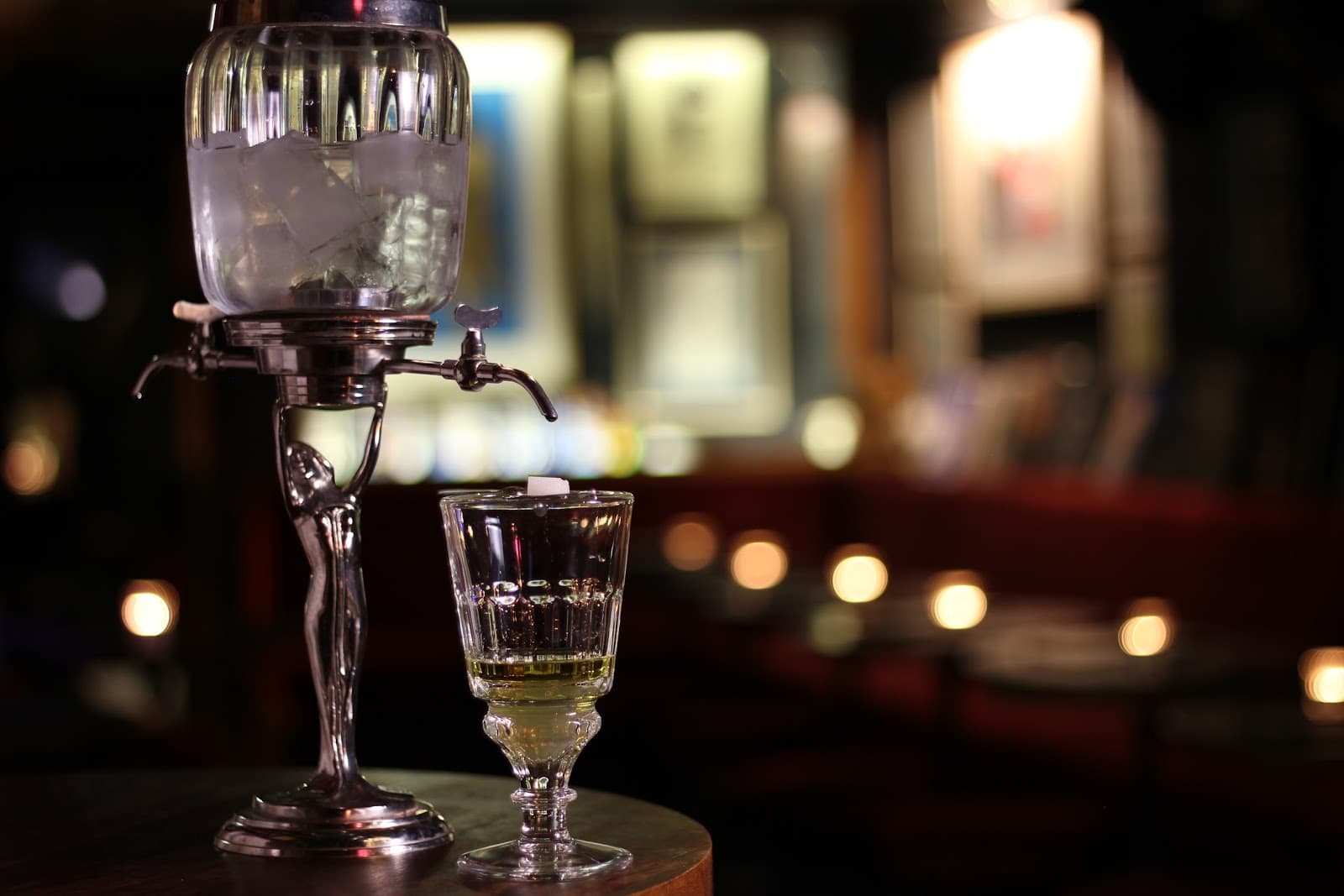 Absinthe fountain and glass on dimly lit bar counter in London