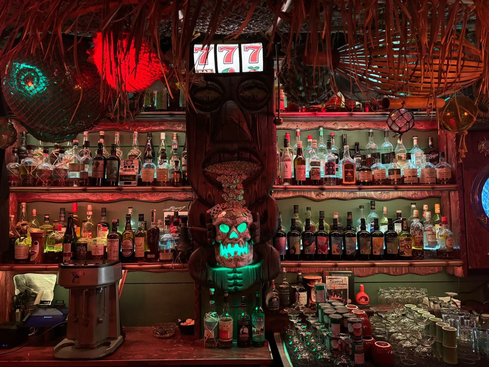 Tiki-themed bar with bottles and a carved wooden statue