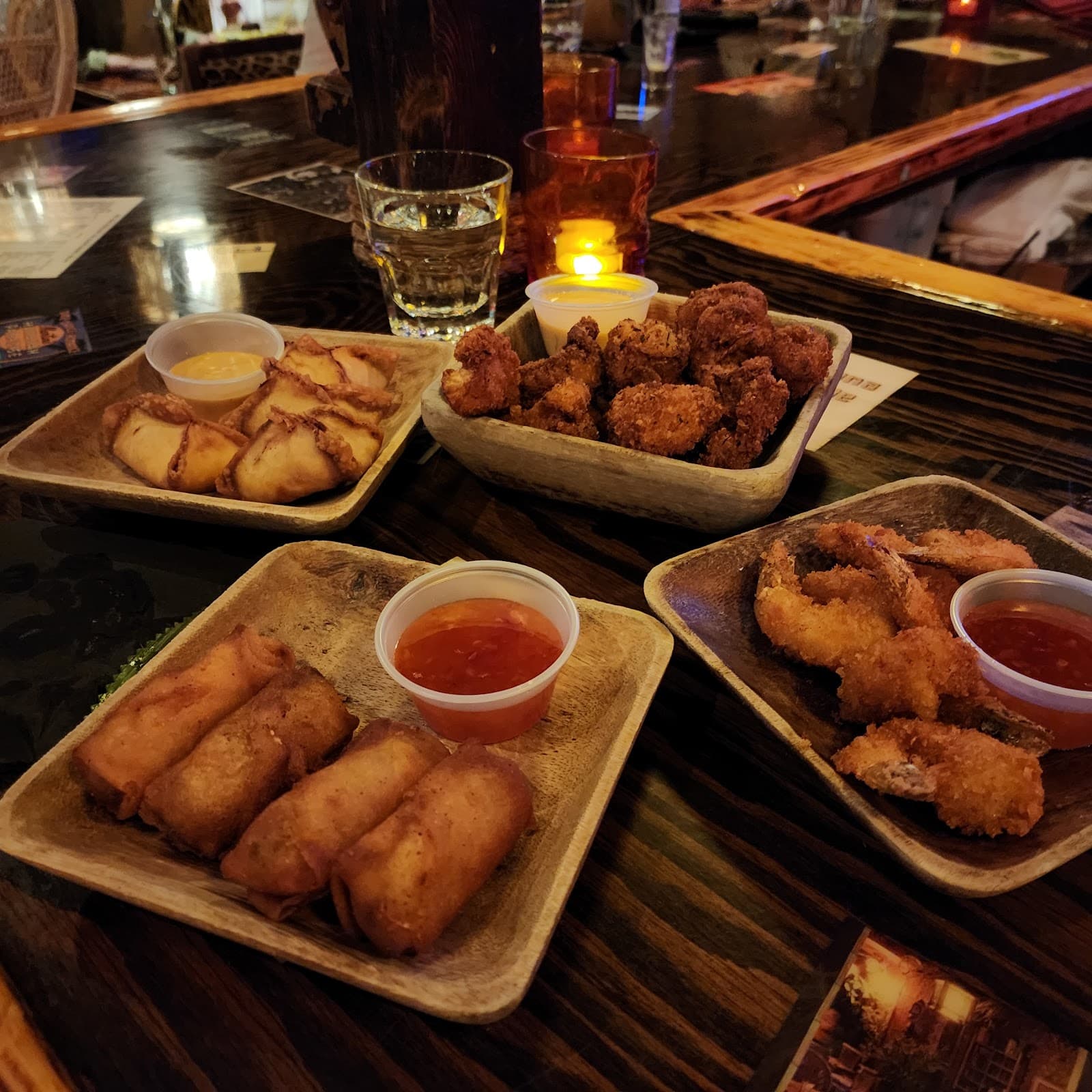 Assorted appetizers on a dimly lit bar counter with candles in Toronto
