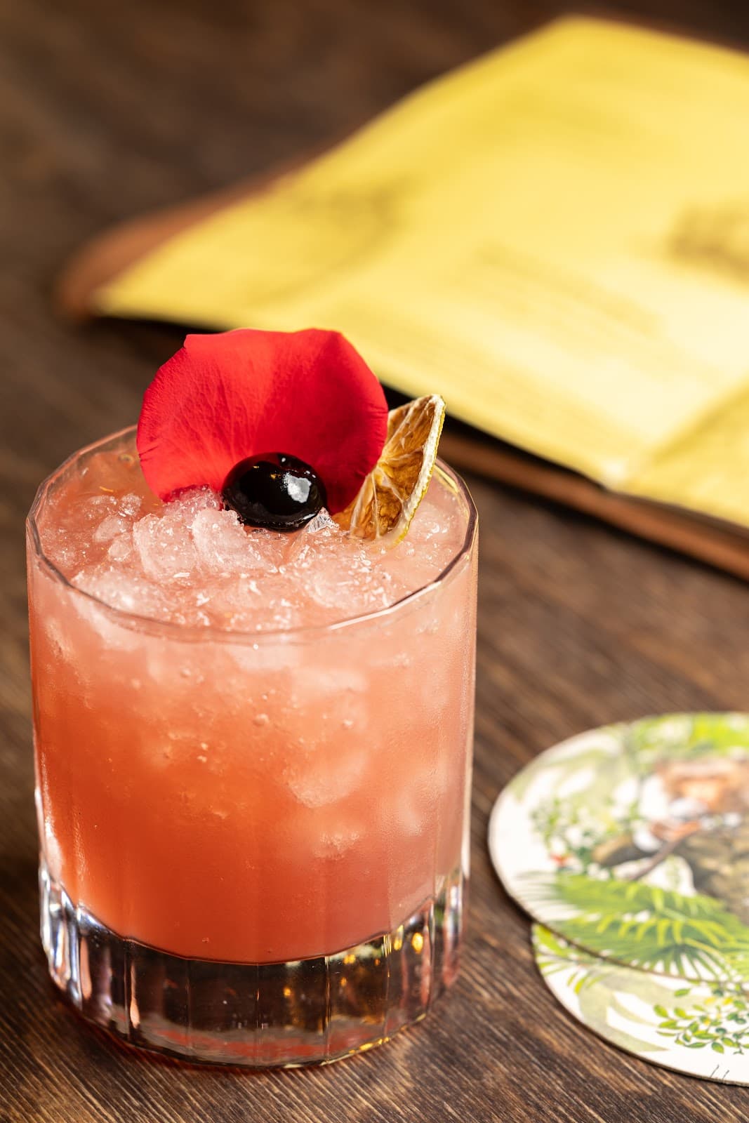 Elegant cocktail with red petal garnish on a wooden table in London