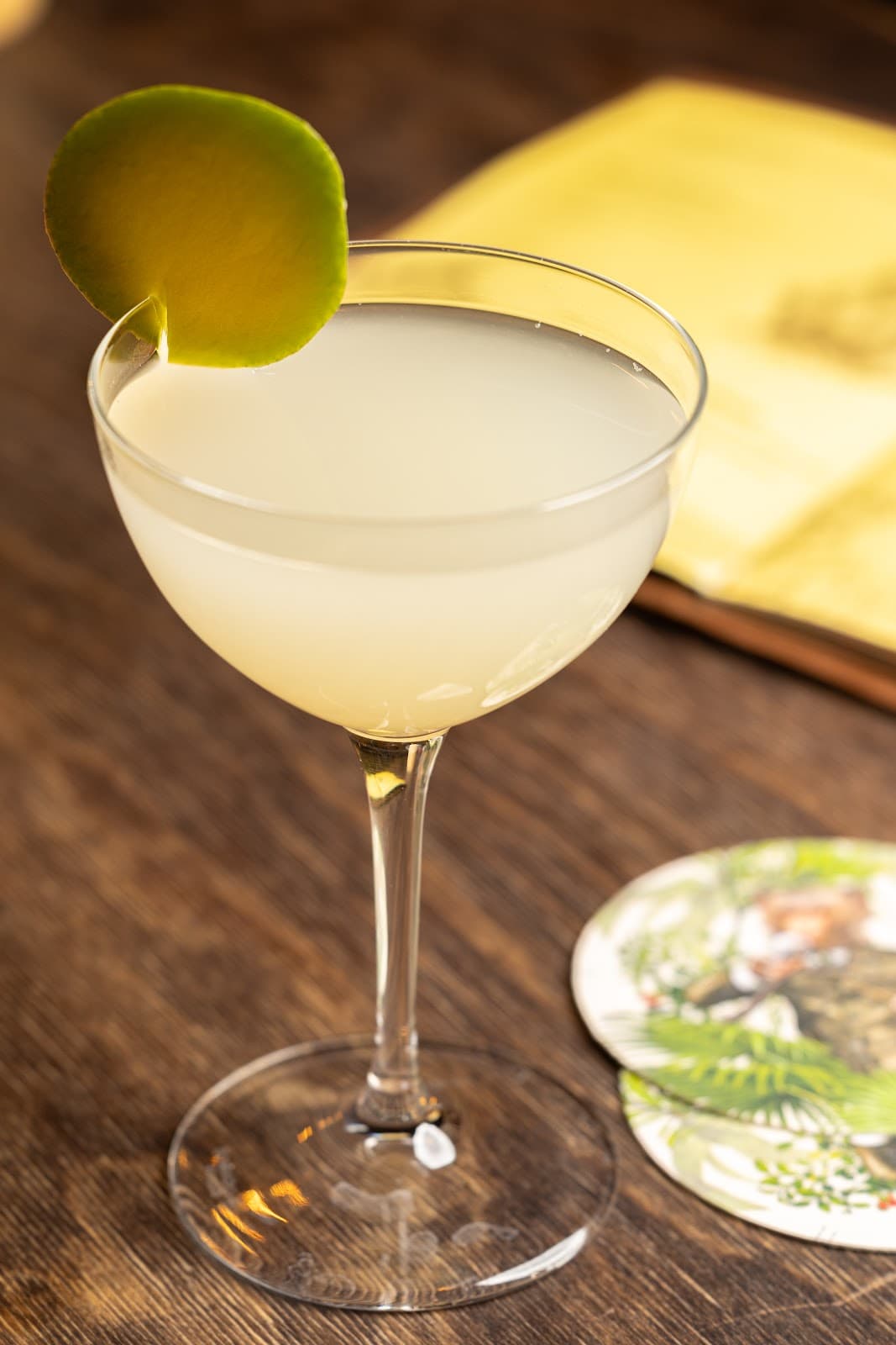 Cocktail in a coupe glass with lime garnish on a wooden table in London