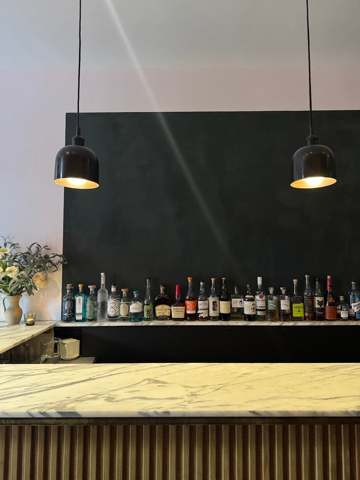 Minimalist bar counter with a variety of liquor bottles and stylish lighting in London