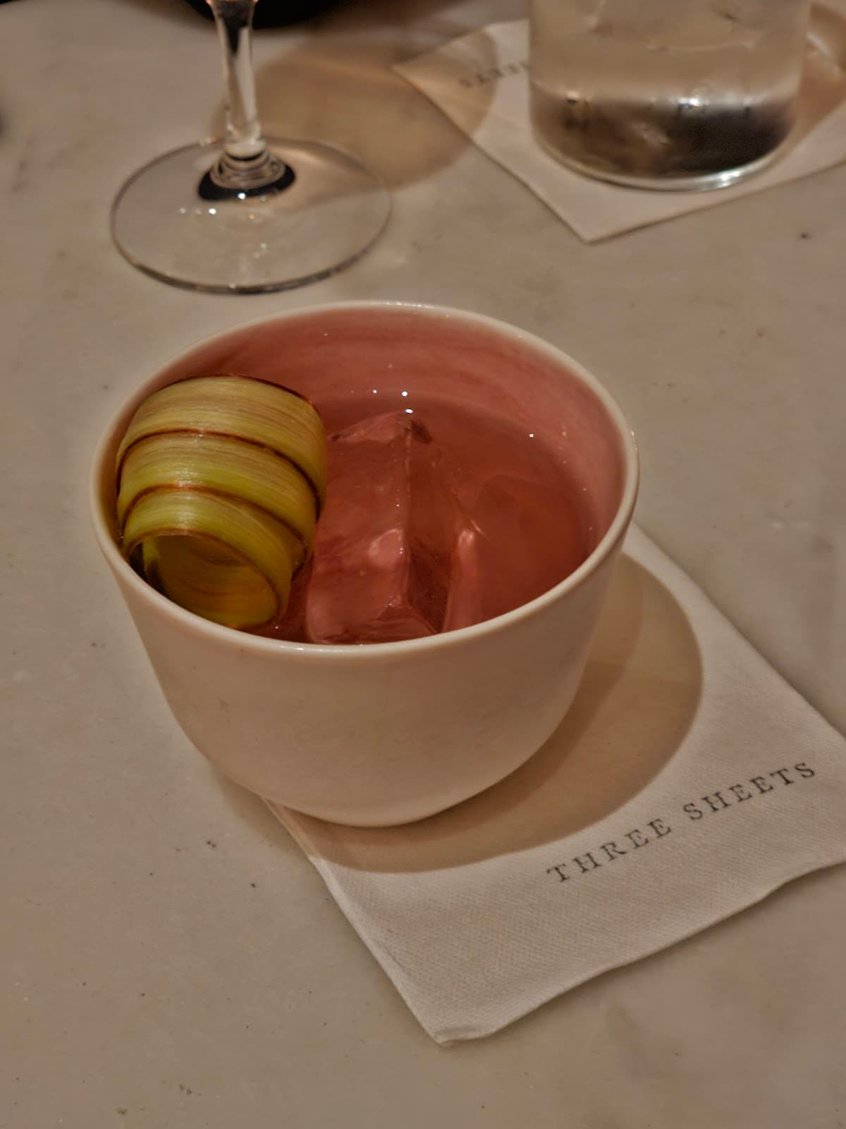 Cocktail served in a cup on a napkin with 'Three Sheets' text in London