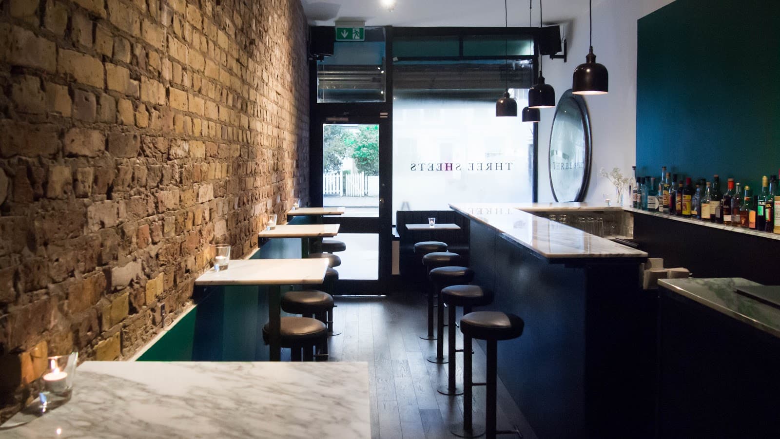 Cozy bar interior with brick walls and marble tables at Three Sheets
