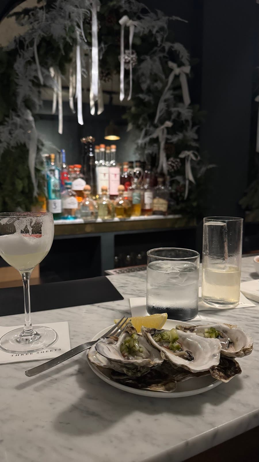 Cocktail bar with oysters on marble counter and bottles in the background in London