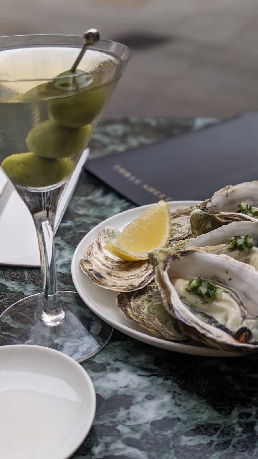 Martini with olives and oysters on marble table