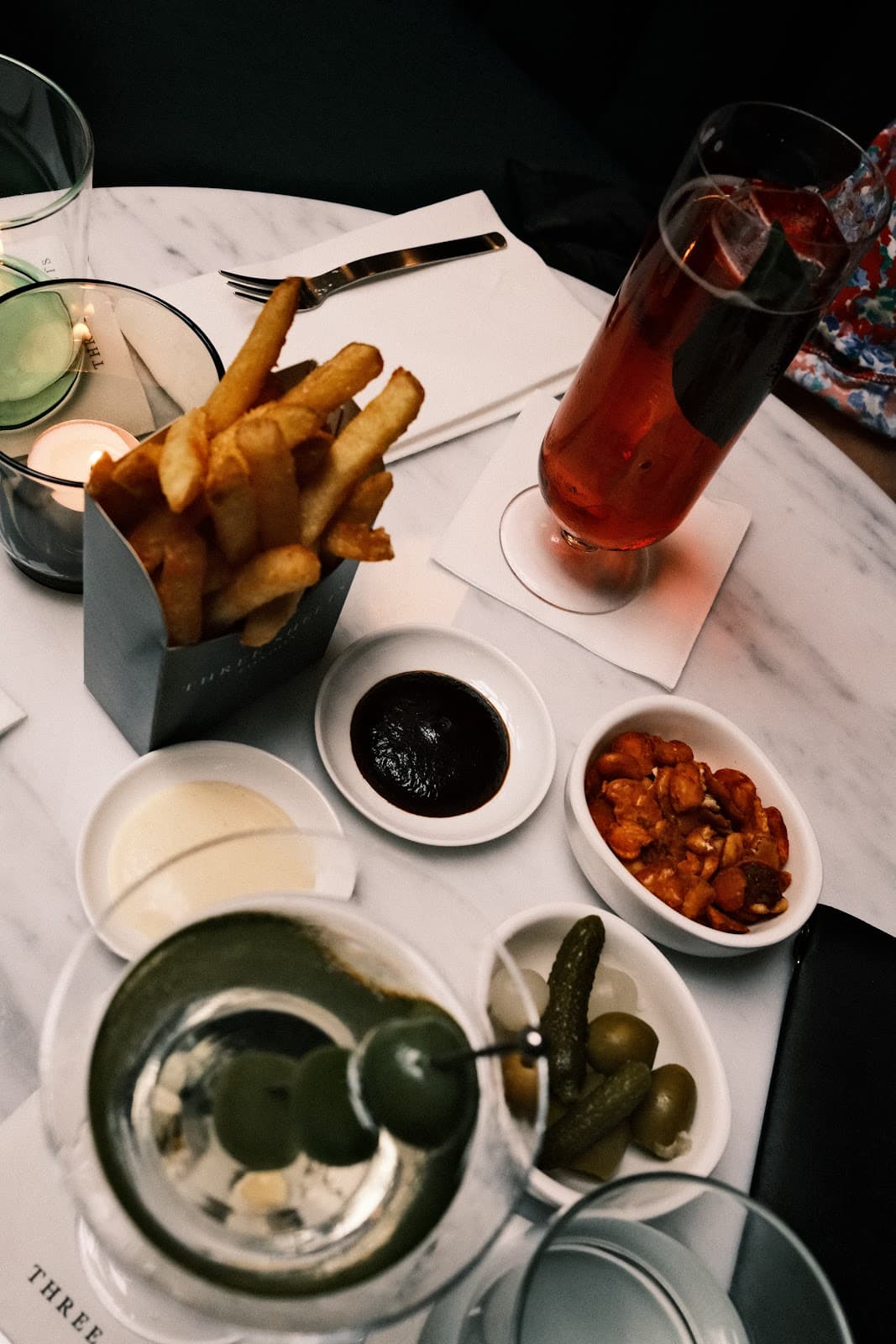 Table with cocktails, fries, and snacks at a premium cocktail bar in London