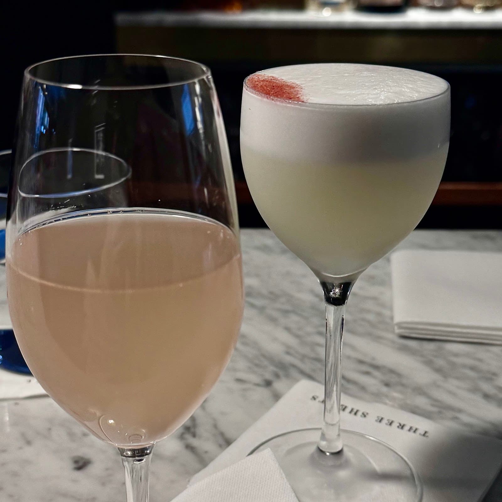 Two cocktails on a marble table at a bar in London