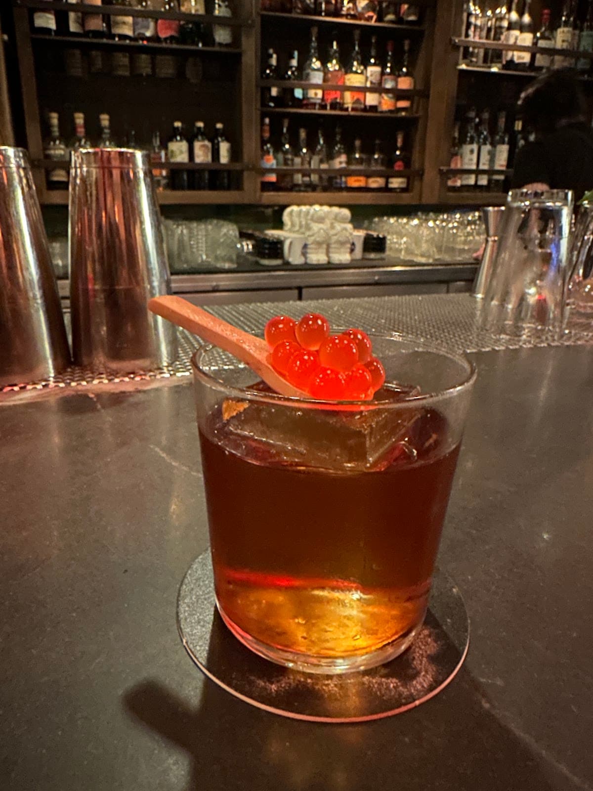Craft cocktail with red spheres on a spoon at a stylish bar in San Francisco