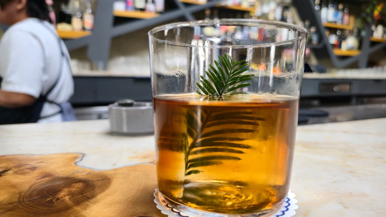 Close-up of a cocktail with a green garnish on a bar counter