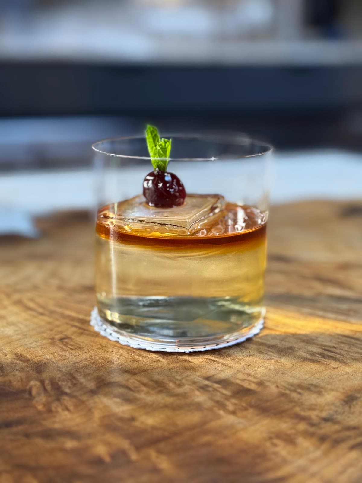 Close-up of a cocktail with a cherry garnish on a wooden table in San Francisco