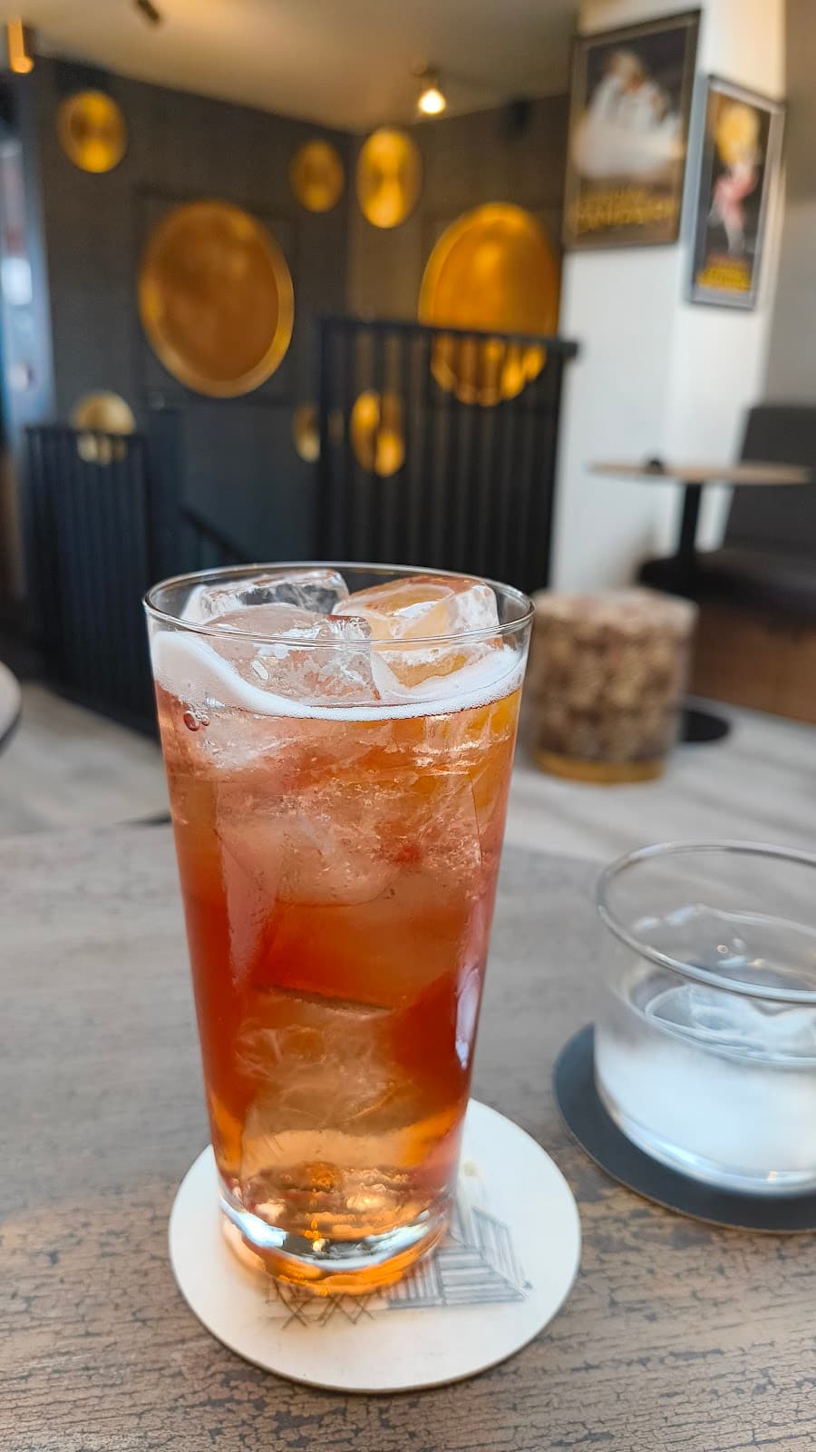 Iced cocktail on wooden table with modern decor in the background in London