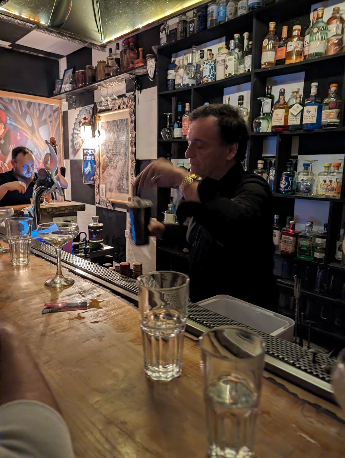 Bartender preparing drink at a bar with bottles on shelves in Lisboa