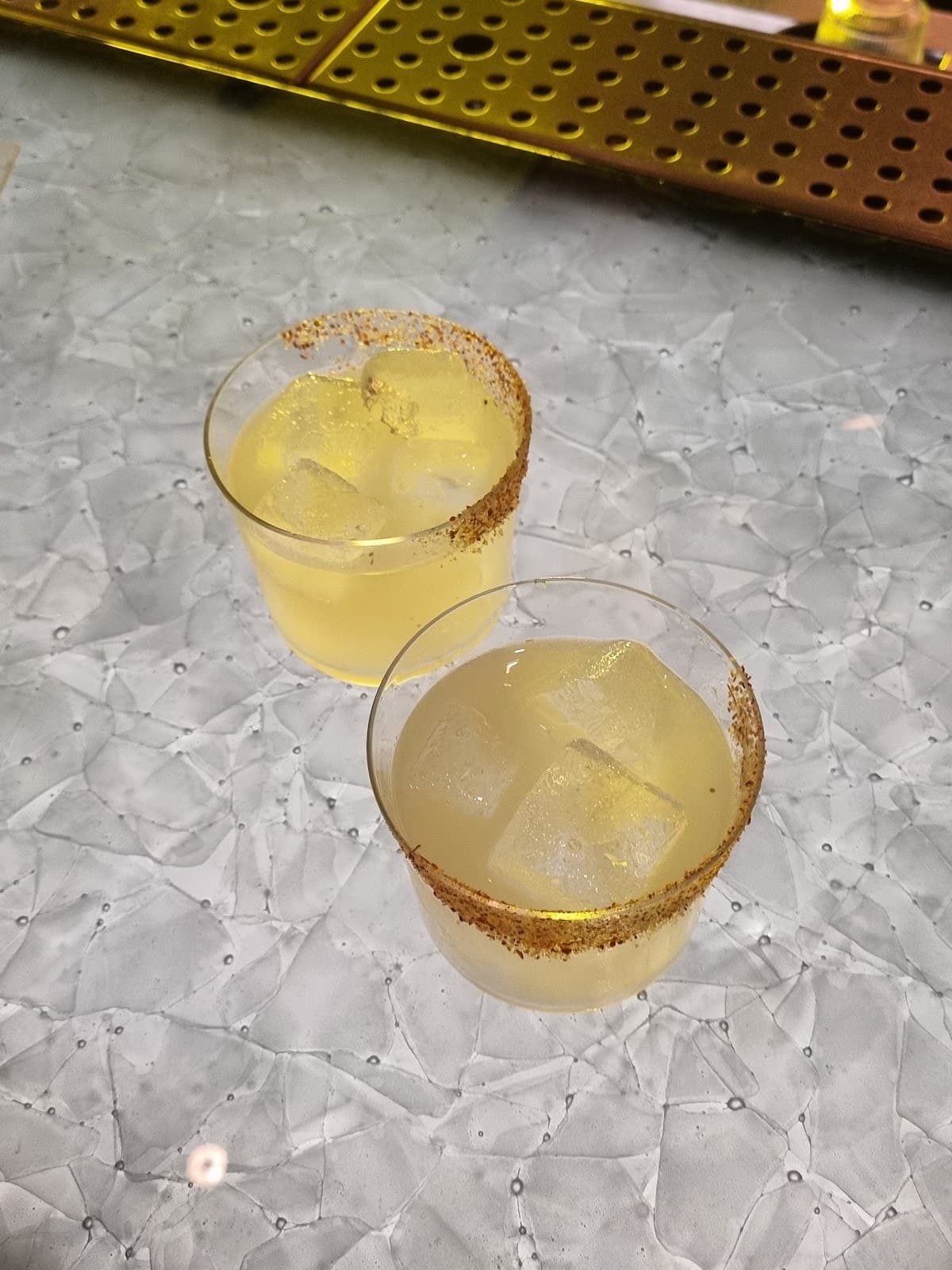 Two cocktails with ice and spice rim on a textured table in London