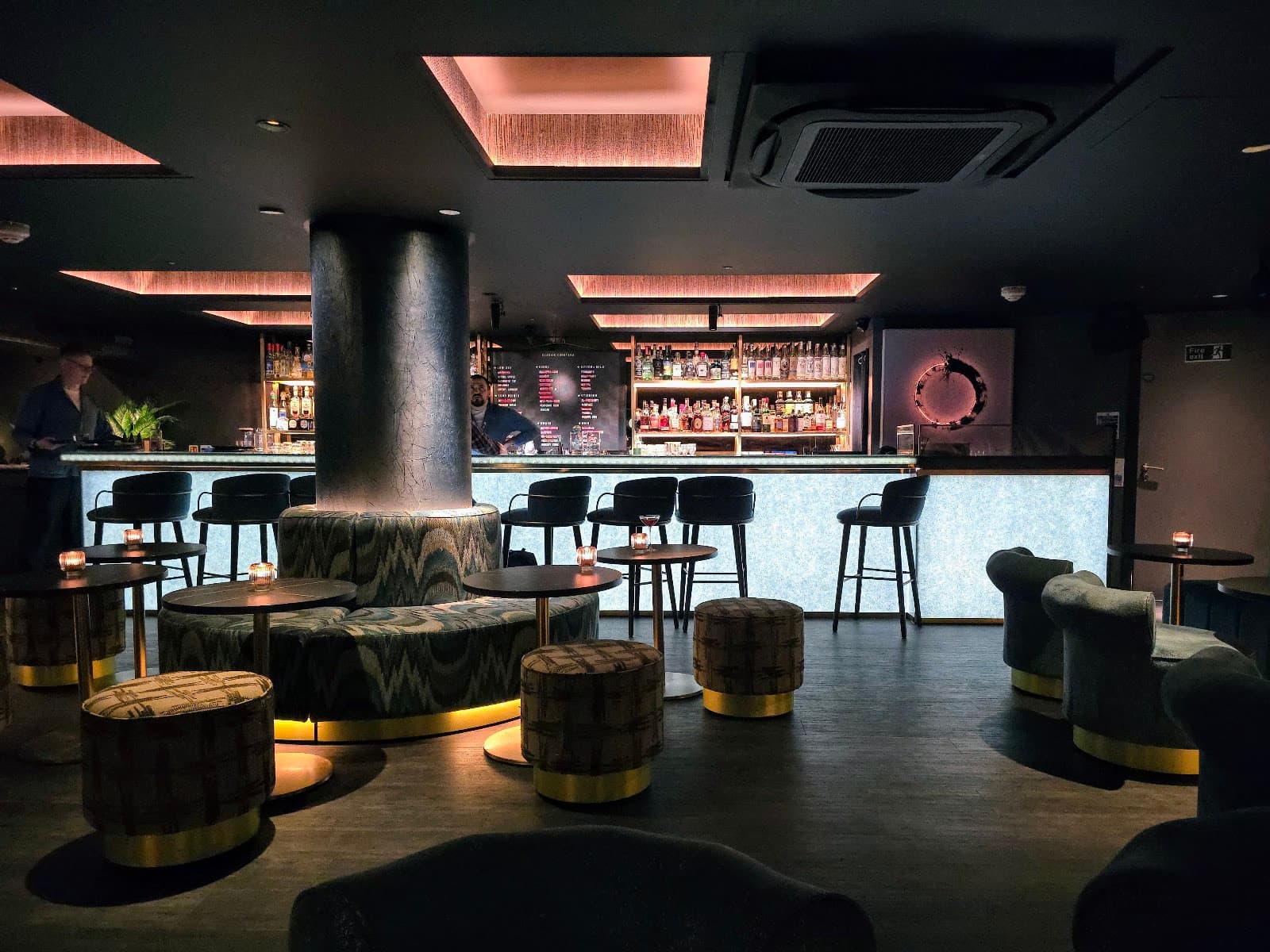 Stylish cocktail bar interior with modern seating and backlit bar in London