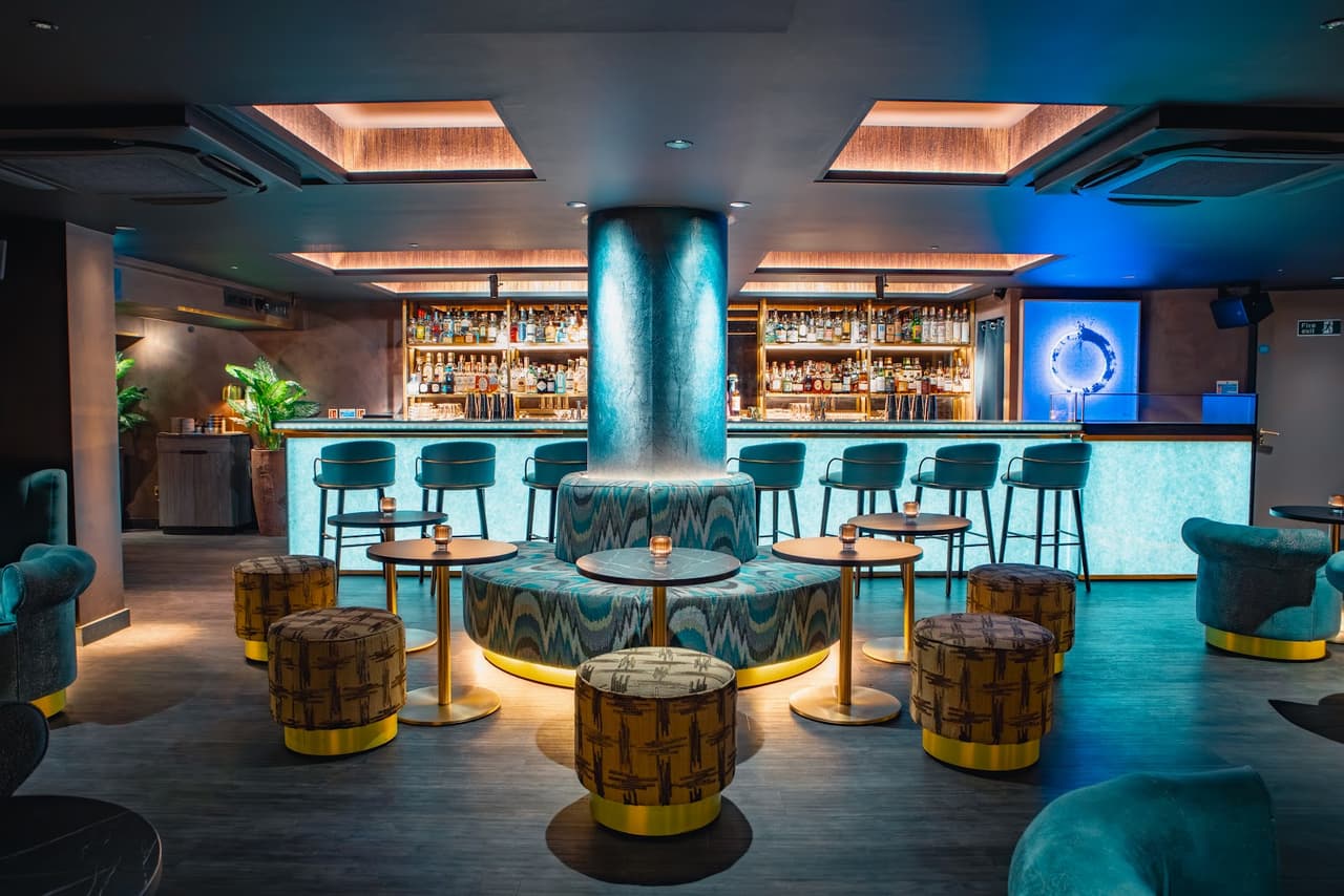 Chic cocktail bar interior with modern stools and illuminated bar counter
